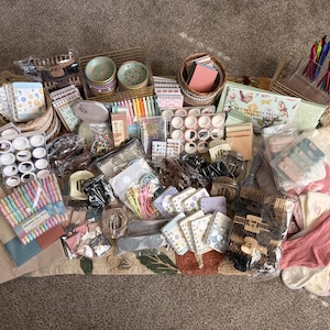 Puede incluir: Una colecci&oacute;n de art&iacute;culos de papeler&iacute;a y accesorios que incluye bol&iacute;grafos de colores, varios rollos de cinta washi, cuadernos peque&ntilde;os con motivos florales, pinzas para el cabello, calcetines y platos de cer&aacute;mica, todo en un gran surtido.