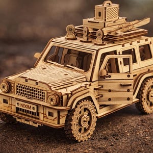 Może przedstawiać: Szczegółowy drewniany model pojazdu 4x4 z otwartymi drzwiami, z misternymi detalami wyciętymi laserowo. Model zawiera bagażnik dachowy, reflektory i koło zapasowe. Pojazd wykonany jest z jasnego drewna.