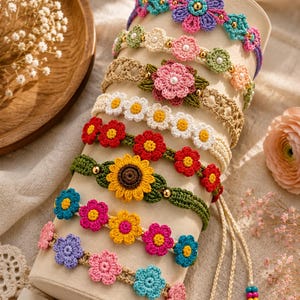May include: A collection of eight colorful crochet flower bracelets displayed on a cylindrical stand. Each bracelet features intricate yarn-stitched floral patterns in various hues, accented with small beads, and finished with adjustable braided ties.