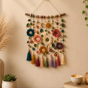 Può includere: Un arazzo da parete fatto a mano con fiori all'uncinetto in vari colori, tra cui turchese, rosa e giallo. Il design floreale è accentuato da foglie verdi, perline di legno e nappe colorate. La decorazione murale è sospesa da un ramo di legno.