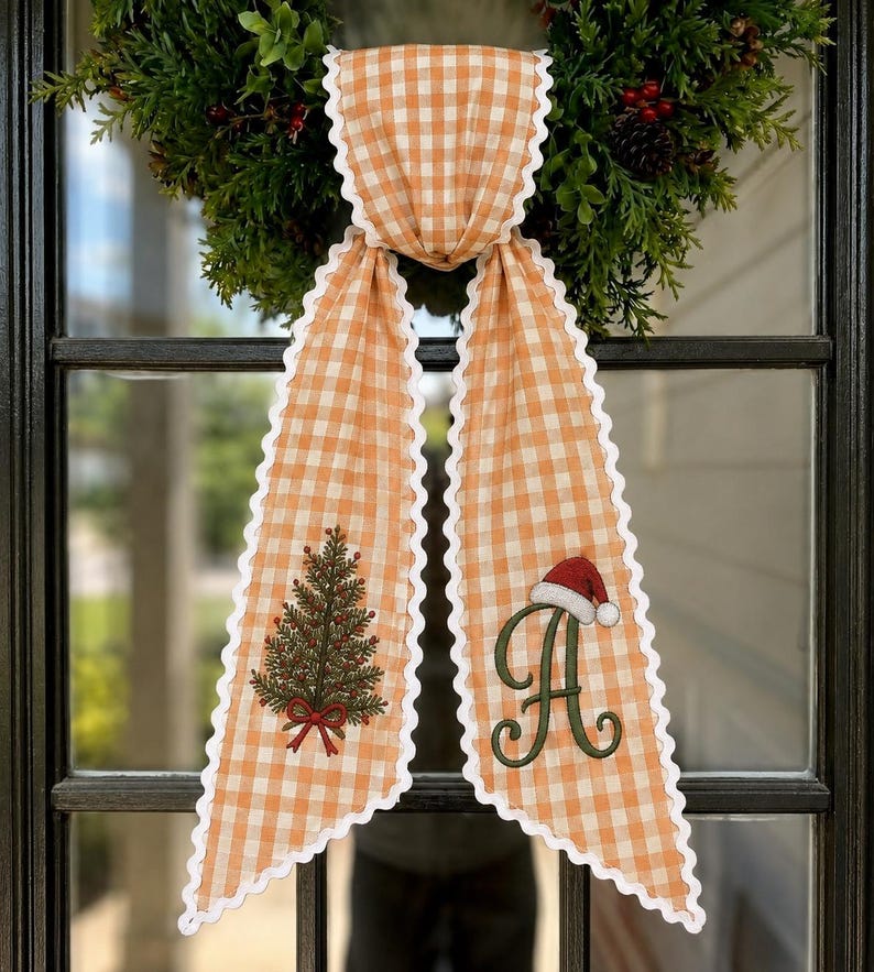 May include: A long orange and white gingham ribbon with scalloped white edges. The left side features an embroidered green Christmas tree with a red bow, and the right side displays a large green letter A topped with a red and white Santa hat.