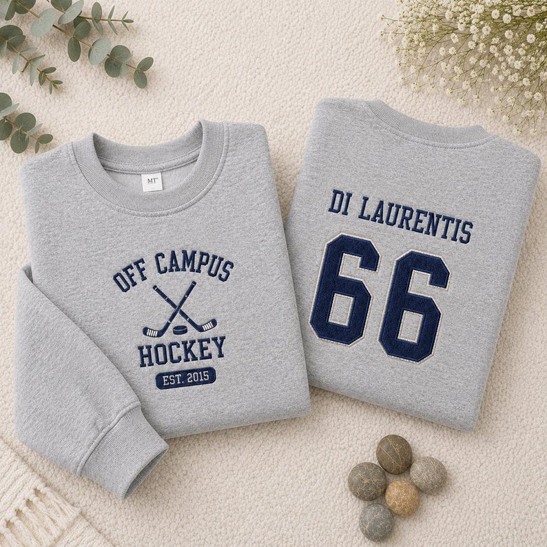 Puede incluir: Dos sudaderas grises. Una presenta "OFF CAMPUS HOCKEY EST. 2015" con palos de hockey cruzados en azul marino. La otra tiene "DI LAURENTIS" y el n&uacute;mero "66" en azul marino. Ambas son de cuello redondo.
