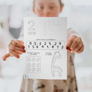 Può includere: Un foglio di lavoro bianco con il numero 2 e la parola "DOS" stampati in alto. Il foglio di lavoro include attività di tracciamento, cerchiatura e colorazione dei numeri. È presente anche un'illustrazione di una giraffa.