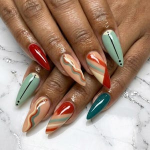 May include: Almond-shaped nails featuring a multi-colored manicure with shades of sage green, deep red, dark teal, and beige. The design includes wavy lines, solid color blocks, and thin vertical black lines with small dots on a glossy finish.