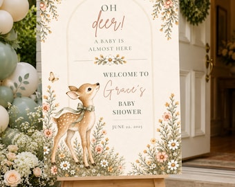 Puede incluir: Un letrero rectangular de bienvenida para baby shower sobre un caballete de madera con una ilustración de un cervatillo con cinta verde, detalles florales y el texto: Oh deer! A baby is almost here, Welcome to Grace's Baby Shower y 22 de junio 2025.