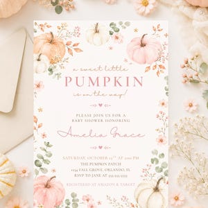 May include: A rectangular baby shower invitation card featuring watercolor illustrations of pale pink and white pumpkins, autumn leaves, and small flowers. The text reads: a sweet little PUMPKIN is on the way! PLEASE JOIN US FOR A BABY SHOWER HONORING Amelia Grace SATURDAY, OCTOBER 13TH AT 2:00 PM THE PUMPKIN PATCH 1234 FALL GROVE, ORLANDO, FL RSVP TO JANE AT 555-555-5555 REGISTERED AT AMAZON & TARGET.