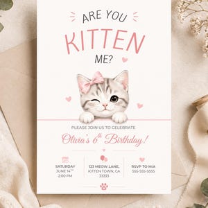 Może przedstawiać: Jasnoróżowa i biała karta zaproszenia z napisem "Are you Kitten Me?" i uroczym kreskówkowym kotkiem z różową kokardą. Karta jest na 6. urodziny Olivii i zawiera szczegóły wydarzenia.