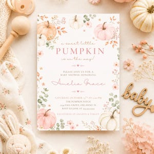 May include: A rectangular baby shower invitation card featuring watercolor illustrations of pumpkins, eucalyptus leaves, and small pink flowers. The text reads: a sweet little PUMPKIN is on the way! PLEASE JOIN US FOR A BABY SHOWER HONORING Amelia Grace.
