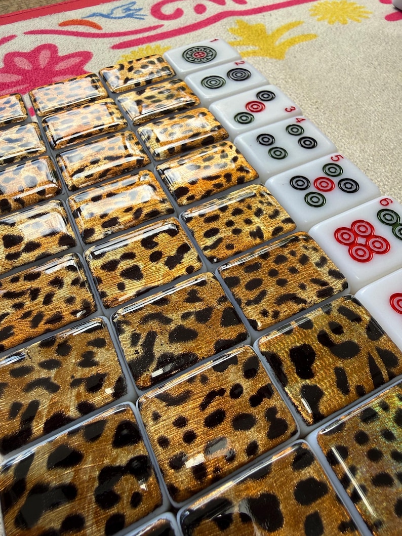 May include: A set of rectangular mahjong tiles arranged in rows. The majority of the tiles feature a glossy gold and black leopard print pattern. A column of white tiles on the right side displays red, green, and black circular dot symbols.