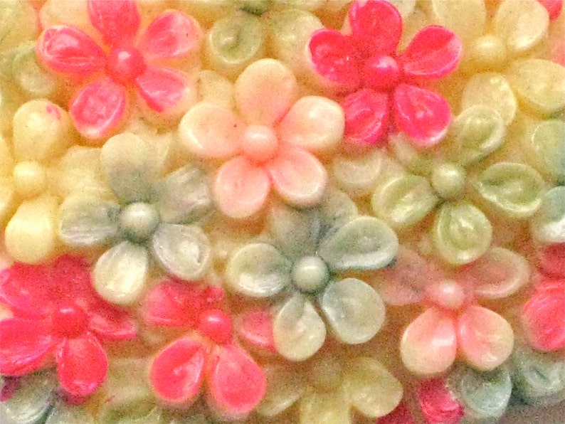 Puede incluir: Primer plano de un grupo de peque&ntilde;as flores de colores pastel. Las flores est&aacute;n hechas de un material liso y brillante y tienen un ligero brillo iridiscente. Las flores est&aacute;n dispuestas en un patr&oacute;n aleatorio, creando un dise&ntilde;o visualmente atractivo y delicado.