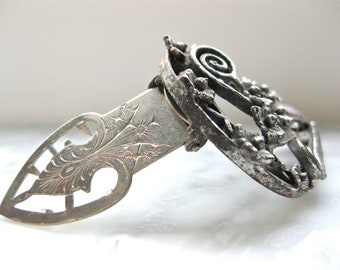 May include: An antique silver letter opener with a decorative floral design and a scrollwork handle. The opener has a pointed blade and a detailed, openwork design. The handle features a spiral element and small floral accents.