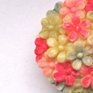 Puede incluir: Un grupo de flores de pl&aacute;stico de color rosa, blanco y verde. Las flores est&aacute;n dispuestas en forma circular y tienen un acabado brillante.