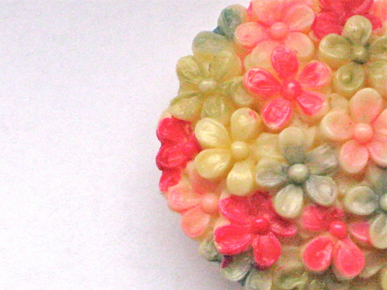 Puede incluir: Un grupo de flores de pl&aacute;stico de color rosa, blanco y verde. Las flores est&aacute;n dispuestas en forma circular y tienen un acabado brillante.