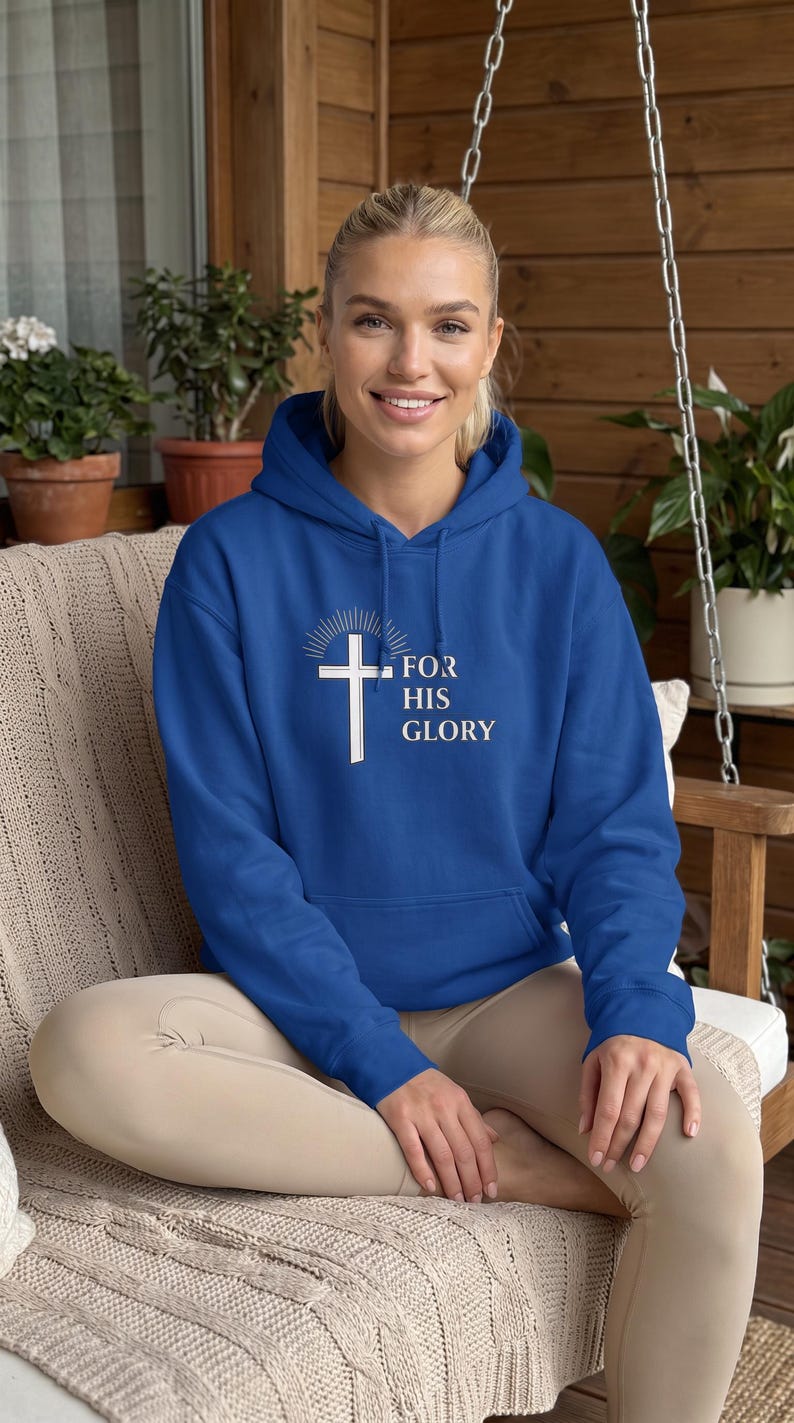 May include: A royal blue hooded sweatshirt featuring a white graphic of a cross with a sunburst design above it and the text "FOR HIS GLORY" printed in white lettering on the front center, including a front kangaroo pocket and long sleeves.