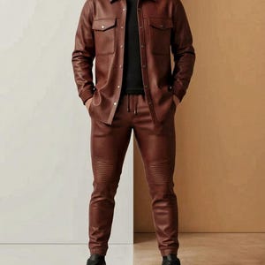 Puede incluir: Una camisa de cuero marr&oacute;n con dos bolsillos en el pecho y pantalones de cuero marr&oacute;n a juego. Los pantalones tienen un dise&ntilde;o acanalado en las rodillas. El conjunto se combina con zapatillas negras. El modelo lleva una camiseta negra debajo.