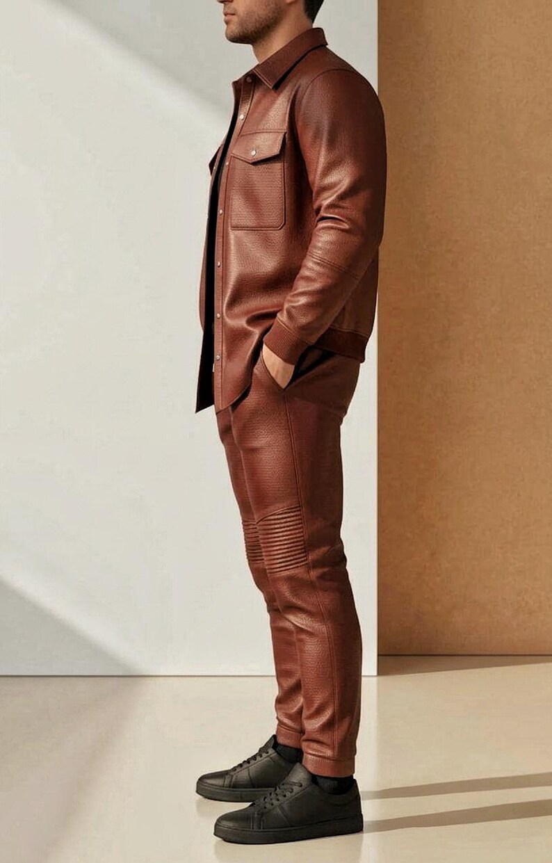 Puede incluir: Un conjunto de camisa y pantal&oacute;n de cuero marr&oacute;n. La camisa tiene dos bolsillos en el pecho y una botonadura. Los pantalones tienen un dise&ntilde;o acanalado en las rodillas. La persona lleva zapatillas negras.