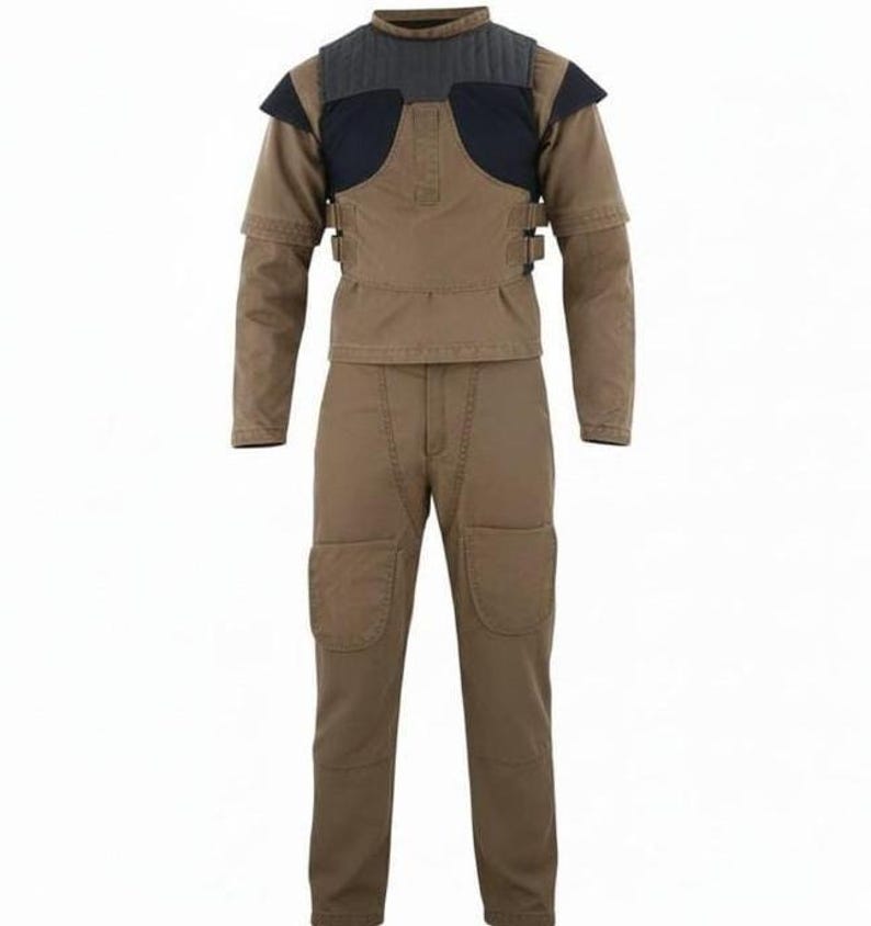 May include: A tan long-sleeved shirt and matching pants set featuring a dark charcoal quilted chest panel, shoulder accents, and side buckle straps. The pants include reinforced knee patches, creating a structured utility-style outfit.