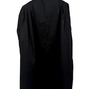 Puede incluir: Una toga acad&eacute;mica larga de color negro con un dise&ntilde;o de hombros estructurado y pliegues verticales profundos que se extienden por la espalda. La prenda se muestra sobre un maniqu&iacute;, exhibiendo un cuello alto y tejido negro opaco.