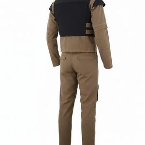 May include: A tan long-sleeved jacket and matching trousers set. The jacket features a black panel across the upper back and shoulders. The trousers have two back pockets and a straight-leg cut. The entire outfit is made of a solid tan fabric.