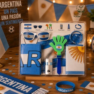 Op de afbeelding: Een doorzichtige plastic verpakking met Argentinië-thema fanaccessoires. Inclusief zonnebrillen, een cheer clapper, schmink, een sjaal, een siliconen armband en andere items in blauw en wit, met het Argentijnse vlagontwerp.