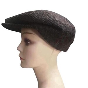 May include: A dark brown flat cap featuring a subtle herringbone pattern. The cap has a rounded crown and a short, stiff brim extending from the front. The fabric displays a textured weave with darker brown and black threads throughout the design.