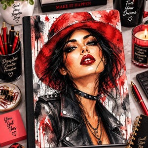 May include: A rectangular notebook featuring a watercolor-style illustration of a person with dark hair wearing a wide-brimmed red hat, a black leather jacket with silver studs, and a spiked choker, set against a white background with red and black paint splatters.