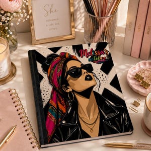May include: A rectangular notebook featuring a graphic illustration of a person wearing sunglasses, a black jacket, and a colourful patterned headscarf. The cover includes the text 'Melissa's notebook' in a stylised font against a black and white background.