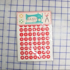 May include: A sheet of red and white sew handy stickers with numbers 1-24, a heart, scissors, a sewing machine, a button, and a pin. The stickers are packaged in a clear plastic bag.