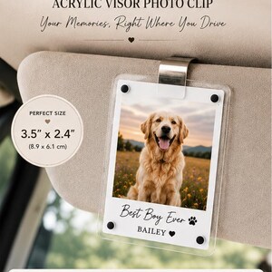 May include: A clear acrylic visor photo clip featuring a rectangular frame with a metal attachment. The insert displays a golden retriever in a field with the text Best Boy Ever and BAILEY. It measures 3.5 inches by 2.4 inches.