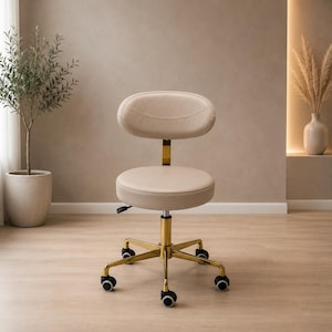 Puede incluir: Un taburete beige con ruedas, respaldo redondeado y asiento circular. El taburete cuenta con una base de metal dorado de cinco patas, cada una equipada con una rueda negra para facilitar el movimiento, y una palanca de ajuste bajo el asiento.