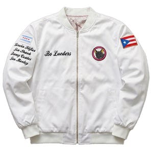 May include: White bomber jacket with a zip-up front, featuring embroidered details. The jacket has a Chicago flag patch, a Puerto Rican flag patch, and a circular patch with a dog illustration. The name "Bo Lueders" is embroidered on the front.