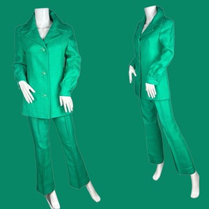 May include: A green pantsuit with a long-sleeved jacket and wide-leg pants. The suit is made of a smooth fabric and has a classic, tailored fit.