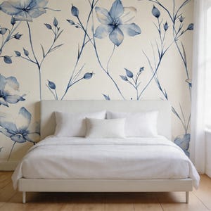 May include: A modern bedroom with a white bed frame and bedding. The headboard is simple and rectangular. The wall behind the bed features a large floral watercolor design in shades of blue and white, creating a serene atmosphere.