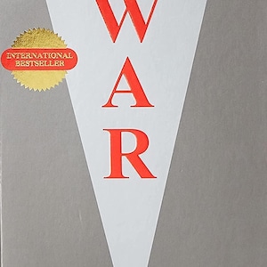 May include: A book titled The Concise 33 Strategies of War by Robert Greene. The cover features a large white triangle on a gray background with the word WAR in bold red letters. A gold circular sticker reads International Bestseller.