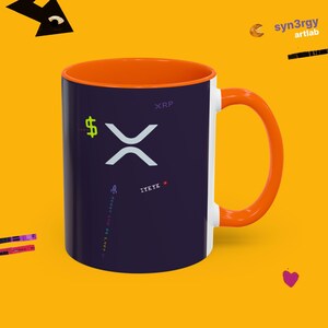 Puede incluir: Una taza de cerámica de color morado oscuro con interior y asa de color naranja brillante. El exterior presenta un logotipo XRP blanco, un signo de dólar verde neón, el texto IYKYK, un icono de cohete y el texto vertical it can't be dirt cheap.