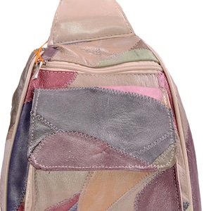 May include: A multi-colored patchwork leather sling backpack featuring various irregular shapes in shades of pink, purple, beige, grey, and green. The bag includes a top zipper closure, a front zippered pocket with a flap, and visible stitching.