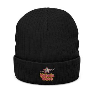 Könnte beinhalten: Schwarze gerippte Mütze mit einem farbenfrohen gestickten Design. Das Design zeigt eine sternartige Form mit den Worten "Nebula Wave" in einer stilisierten Schriftart. Die Mütze ist aus weichem Strickmaterial gefertigt.