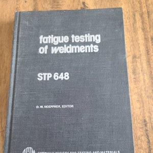 May include: A dark gray book titled "fatigue testing of weldments" with the text "STP 648" and "D. W. HOEPPNER, EDITOR." The book also features the logo and name of the "AMERICAN SOCIETY FOR TESTING AND MATERIALS."