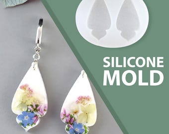 Könnte beinhalten: Tropfenförmige Ohrringe mit gepressten Blumen in Harz, mit blauen, gelben und rosa Blüten. Die Ohrringe hängen an silberfarbenen Haken. Eine Silikonform mit der gleichen Form ist ebenfalls abgebildet, mit dem Text "SILICONE MOLD".