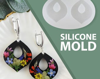 Könnte beinhalten: Schwarze Tropfenohrringe mit bunten Trockenblumen und silbernen Haken. Die Ohrringe werden neben einer Silikonform mit dem Text "SILICONE MOLD" präsentiert. Die Ohrringe haben ein einzigartiges, künstlerisches Design.