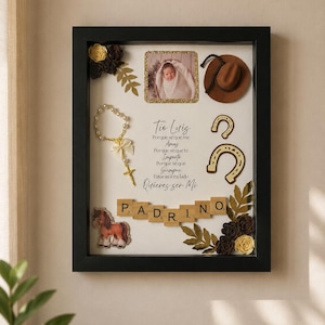 May include: A black shadow box frame containing a photo of a baby, a brown cowboy hat, a rosary, two horseshoes, a horse cutout, and paper flowers. The text reads: Tio Luis Porque se que me Amas Porque se que te Importo Porque se que Siempre Estaras a mi lado Quieres ser Mi PADRINO.