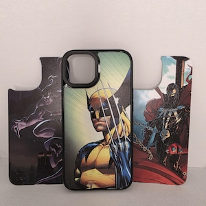 Op de afbeelding: Zwarte telefoonhoes met een stripboekillustratie van Wolverine. De hoes wordt geflankeerd door twee andere stripboekillustraties, een van een donkere figuur en een van Spawn. De hoes heeft een zwarte rand.