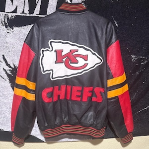 May include: Black leather jacket with red and yellow accents. Features the Kansas City Chiefs logo and the word "CHIEFS" in red. The jacket has a striped collar and cuffs.