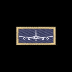 May include: A rectangular embroidered patch featuring a blue denim-textured background with a white stitched airplane silhouette in the center. The patch is bordered by a thick, textured gold-colored thread frame with a frayed, fringe-like edge.