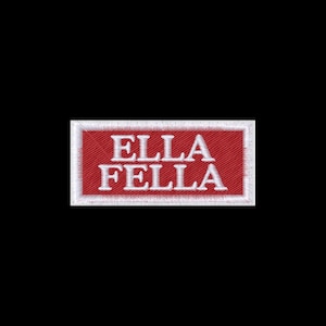 May include: A rectangular embroidered patch featuring a red background with a white border. The text ELLA FELLA is stitched in white capital letters across the center of the patch. The embroidery has a visible texture and a clean, finished edge.