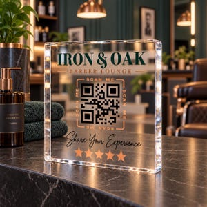 May include: A clear acrylic square sign featuring the text IRON & OAK BARBER LOUNGE, a central QR code with the words SCAN ME, the phrase Share Your Experience, and five orange stars. The sign is illuminated with small lights along the edges.