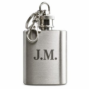 May include: A brushed silver metal flask with a rectangular shape and rounded corners. The front features the engraved letters J.M. in a dark serif font. A silver metal screw-top cap is attached to a silver keyring with a lobster claw clasp.