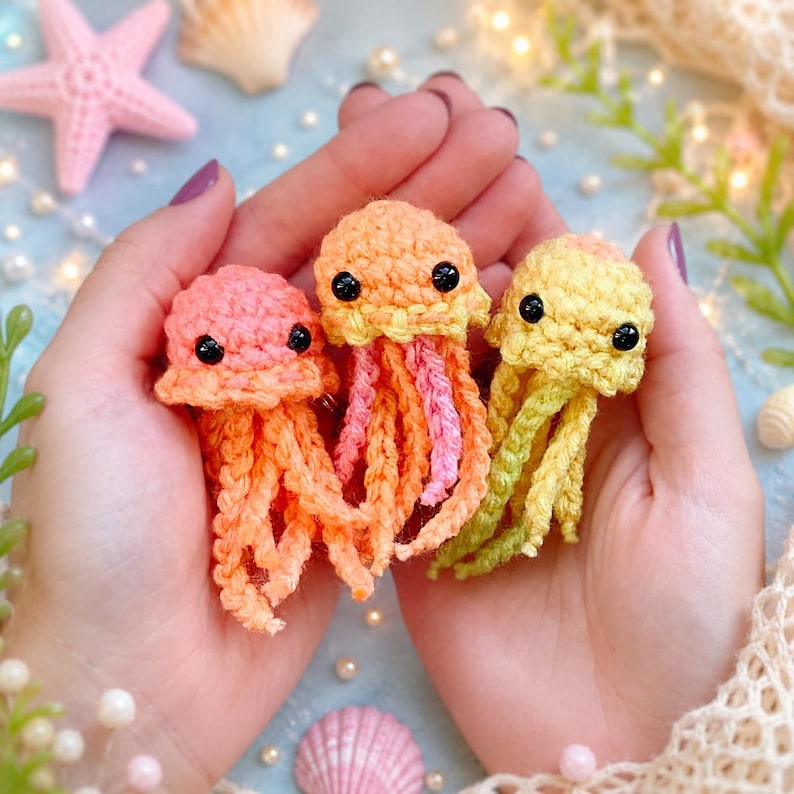 Finished pastel jellyfish amigurumi crochet toy with soft trailing tentacles resting on a knit blanket