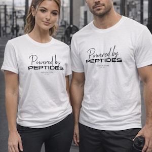 Puede incluir: Dos personas vestidas con camisetas blancas con el texto "Powered by PEPTIDES FASHION STORE EST. 2021" en negro. La persona de la izquierda lleva leggings negros y la de la derecha, pantalones cortos negros. El fondo es un gimnasio.