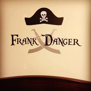 May include: A black and white pirate-themed wall decal with the text "FRANK DANGER" and a skull and crossbones design. The decal features a pirate hat with a skull and crossbones design and two crossed swords.